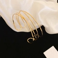 Vista dettagliata del bracciale rigido dorato a più strati su pregiato tessuto di seta bianca - Oro