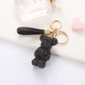 Detail shot of black rhinestone bear keychain with gold clasp and sparkling strap on display - Black