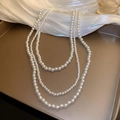 Elegante collana di perle barocche bianche a più strati su un vassoio dorato - Stile Perla a Tre File Bianco