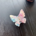 Detailed top view of a gradient butterfly hair claw with marble texture on wood - Iridescent Pink Blue