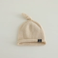 Detalle del gorro de punto crema para bebé con nudo decorativo y borde enrollado - 6 meses - 2 años / Beige