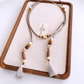 Detailed macro view of bohemian wooden beads and cotton tassels on a natural cord belt - Coffee & Grey