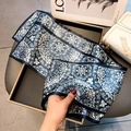 Elegant long silk scarf featuring blue background and white floral patterns on a tray - Medallion Print