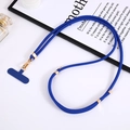 Detail of adjustable blue nylon crossbody phone lanyard with gold metal buckle on a desk - Royal Blue