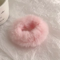 Nahaufnahme des weichen rosa Plüsch-Haargummis mit flauschiger Textur auf Papier - Rosa