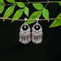 Detailed view of silver hollow carved tassel earrings hanging on a branch with green leaves - E4990-12 (Bohemian Tassel)