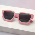 Detail view of pink thick frame rectangular sunglasses on a white geometric stand - Pink Frame Grey Lens