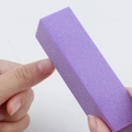 Purple 120 grit four-sided nail buffer block being used to shape and polish nails - Purple