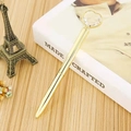 Golden metal ballpoint pen with large heart crystal top on a white hardcover book - Gold