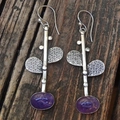 Close-up of vintage metal earrings with purple oval gemstone on a rustic wooden background - Retro Purple Leaf