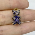 Ciondolo a forma di orso dorato con zirconi blu tenuto tra le dita - Oro Zirconia Blu