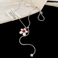 Detailaufnahme der silbernen Schlangenkette mit rotem Blumenanhänger auf schwarzem Grund - Silber Rote Blütenmitte (HN9838)