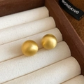 Close-up of golden brushed round stud earrings on a beige textured jewelry tray - 14mm / Gold