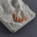 Detailed macro view of 18k gold earrings featuring red marquise zircon on grey stone - Gold Base - Red Zircon