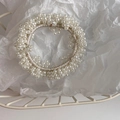 Detailed view of woven beige elastic hair tie with small artificial pearls on paper - Small Pearl