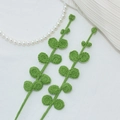 Handmade crochet green leaf branch decor featuring intricate knitted texture on white fabric - Eucalyptus