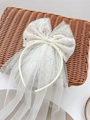 White bridal veil headband with gold stars and bow on a rustic woven basket - Beige Bow Headband