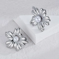Silver flower stud earrings with white faux pearl center on a white geometric prop - E872-01 (Silver Pearl Five-Petal Flower)