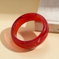 Macro shot of red translucent resin bangle with elegant white ink swirl texture and side lighting - Dark Red Marble Round Bangle