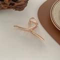Vista dettagliata di un fermaglio per capelli in metallo dorato con design a incrocio - Oro rosa