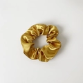 Detailed view of the smooth golden satin texture and folds of the elastic scrunchie - Without Card / Turmeric