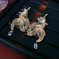 Detail von goldenen Koi-Ohrringen mit klaren Perlen auf schwarzem Schmucktablett - Gold