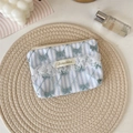 Detailed view of light blue striped lace pouch with butterfly embroidery on woven mat - Vertical Blue