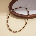 Detail of tiger eye sun pendant necklace with brown beads and silver clasp on a wooden tray - Necklace-Coffee Tiger Eye Irregular