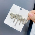 Detailaufnahme einer goldfarbenen Herz-Haarspange mit Kristallbesatz und fließenden Quasten - Drei Herzen Mit Quaste-Gold