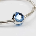 Bracciale a serpente d'argento con un ciondolo in cristallo blu sfaccettato su bianco - Blu Lago/11