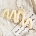 Creamy wavy hair claw clip in a glossy finish on minimalist white decorative paper - White