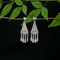 Close-up of silver tassel earrings with hollow patterns on a green leaf branch - E4976-6 (Multi-layer Tassel)