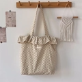 Detail van canvas tote bag met polkadots, ruches aan de rand en geweven merklabel - Beige