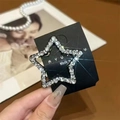 Close-up of star shaped hair clip with sparkling rhinestones on black card packaging - White