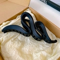 Detail of a matte black S-shaped shark hair claw clip inside a minimalist gift box - Black (Wave)