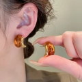 Close-up of geometric amber and gold C-shaped earrings worn by a model in warm light - Gold Plated C-Hoop (45#) / Gold Amber