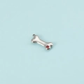 Detailed view of silver bone-shaped pendant with a sparkling red zircon stone inlay - Steel January