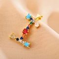 Close-up of golden letter I pendant featuring colorful zircon stones on soft peach fabric - Letter I
