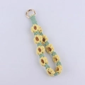 Detailed macro view of handmade woven sunflower keychain with gold metal ring clasp - Yellow