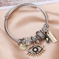 Macro shot of twisted silver bracelet featuring crystal evil eye and handmade charms - Silver-Dark Green Beads