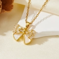 Gros plan détaillé d'un collier pendentif nœud doré avec incrustation nacre et zircons - Style Nœud Coquille Blanche Dorée (T015)