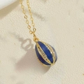 Dettaglio della collana dorata con pendente in smalto blu scuro e strass bianchi decorativi - Blu Reale