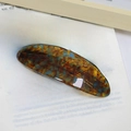 Elegant tortoiseshell acetate hair barrette with blue speckles on a book background - Teal Blue