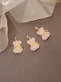 Trois pendentifs ours en résine rose avec nœuds papillon dorés et fermoirs sur fond brun - Rose