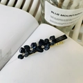 Dettaglio di un fermaglio per capelli a fiore nero in resina con strass e lega dorata - Blu nero