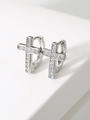 Close-up of silver cross pendant earrings with micro-set zircons on white geometric steps - Silver