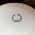 Dettaglio dell'anello aperto argentato con doppia fila di zirconi su ceramica bianca - Argento