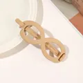 Detail of a matte beige infinity hair claw clip resting on a white ceramic plate - Infinity - Ginger Yellow