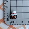 Macro shot of a 1cm mini black resin Halloween pumpkin charm with white hat and scale - Black Pumpkin with White Hat