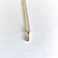 Detailed close-up of a minimalist golden necklace featuring a polished letter J pendant - Letter J